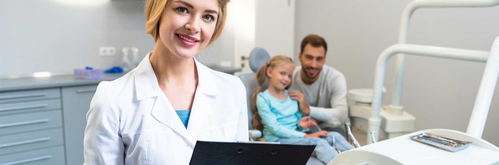 A female dentist holding a record in her hands with a father and child waiting in behind