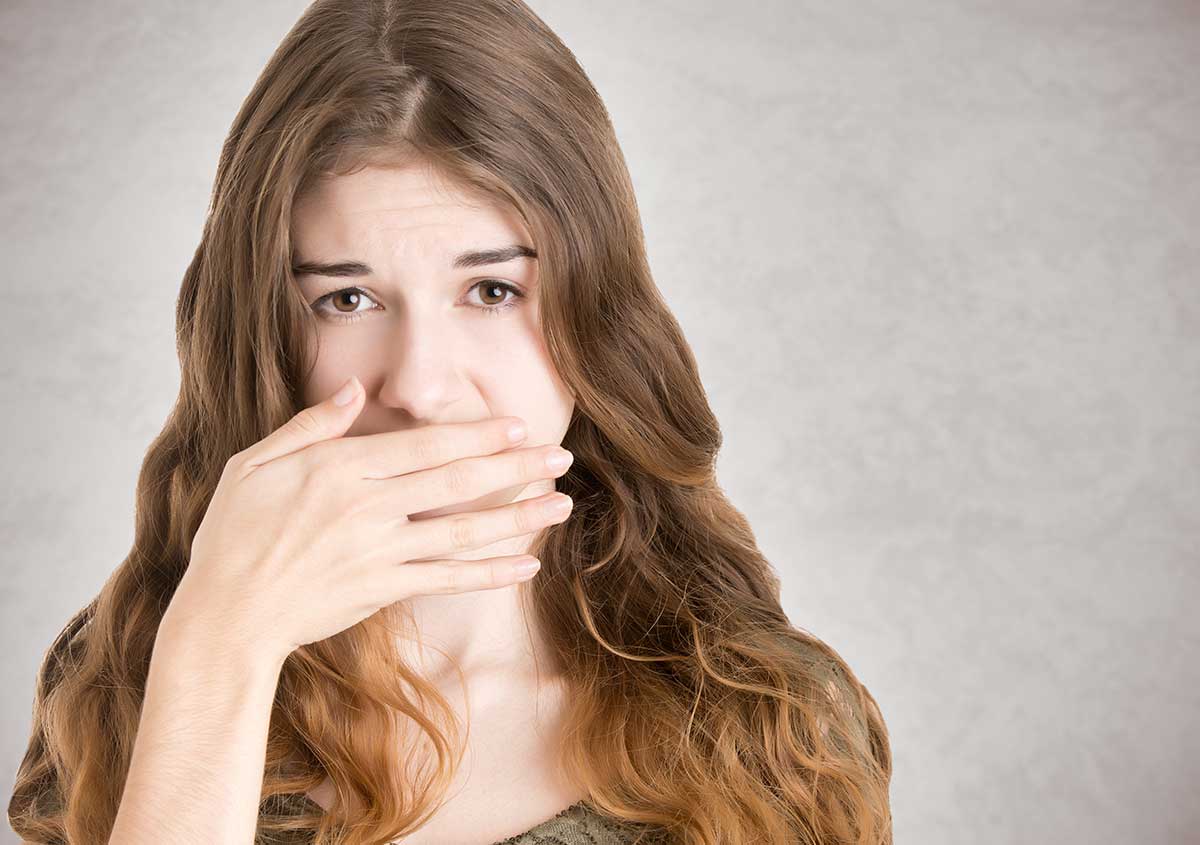 A woman covering her mouth with hands for pain