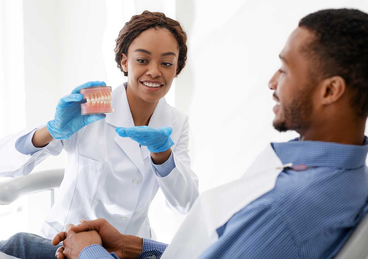 Female dentist explaining to the patient with the tooth model