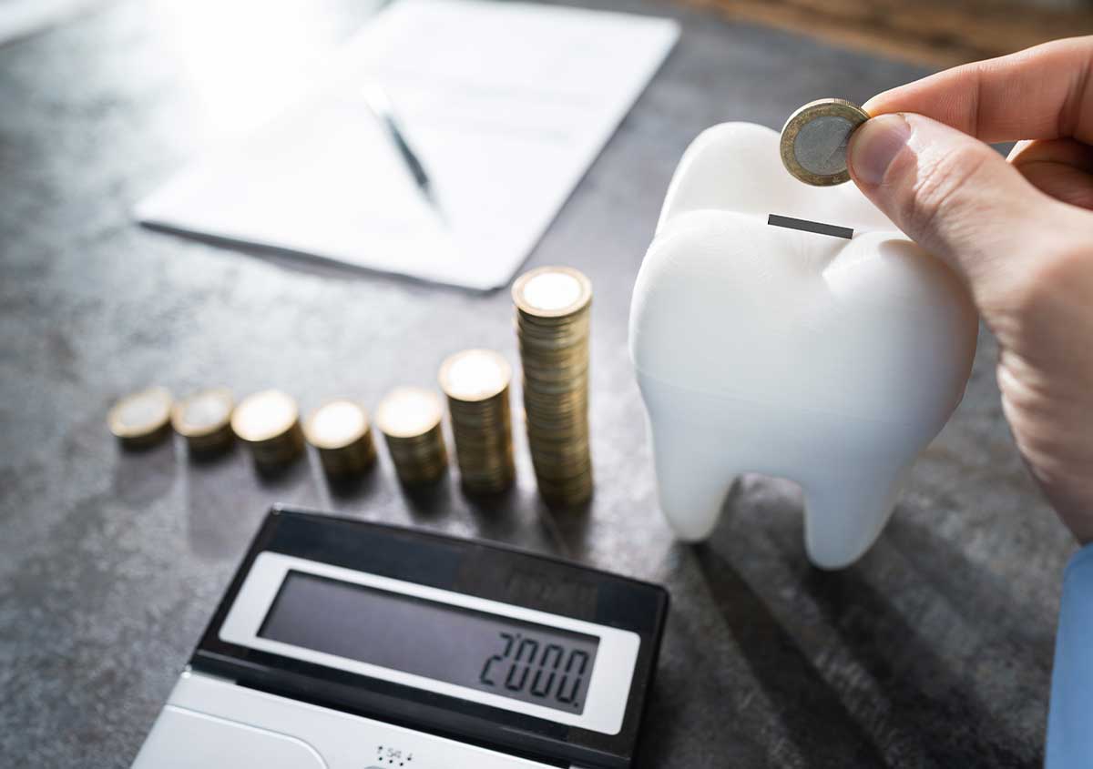 Dental savings - calculator and a bunch of coins on the table alongside a till